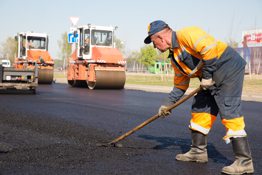 Worker paving asphalt highway